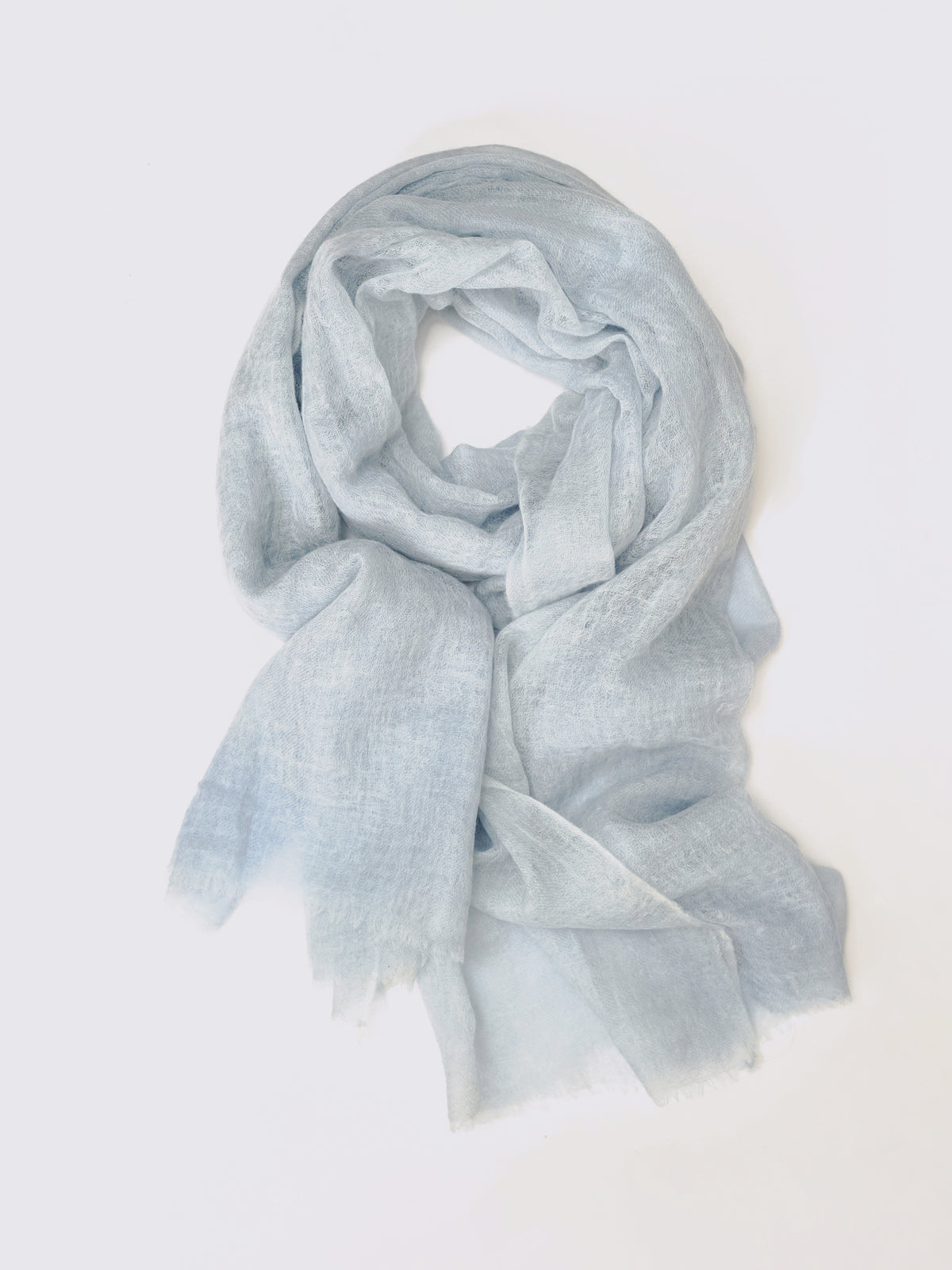 A light blue semi-sheer cashmere scarf with a soft, lightweight texture, draped in a loose loop against a plain white background.