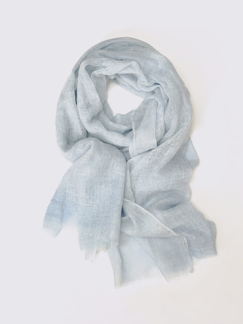 A light blue semi-sheer cashmere scarf with a soft, lightweight texture, draped in a loose loop against a plain white background.